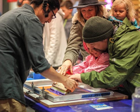A family participating in a printmaking workshop