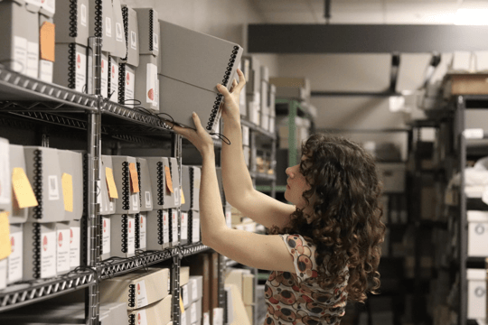 A person placing a collection back on the shelf